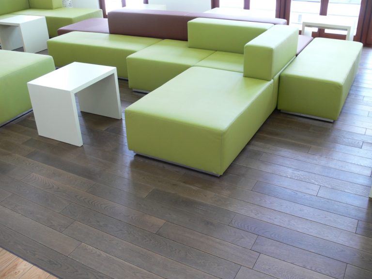 Helle, moderne Lounge mit grünen, modularen Sitzmöbeln und Holzfußboden.
