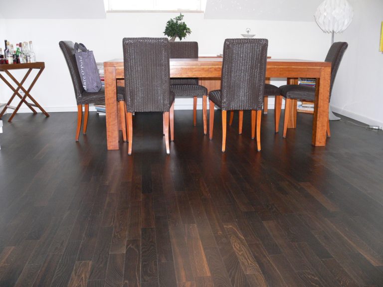 Holzfußboden mit Esstisch und Stühlen in einem hellen Raum.