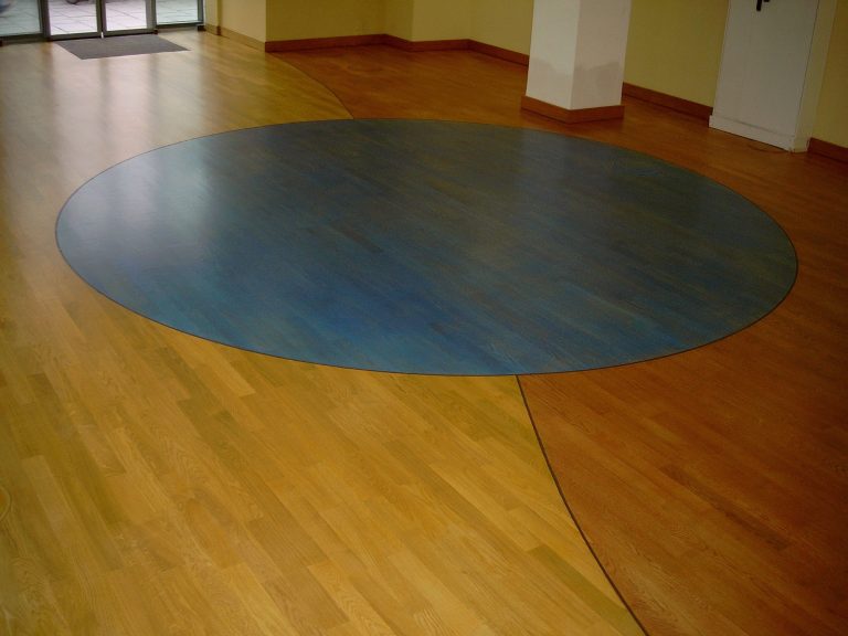 Runder blauer Bereich auf einem Holzfußboden in einem Innenraum.